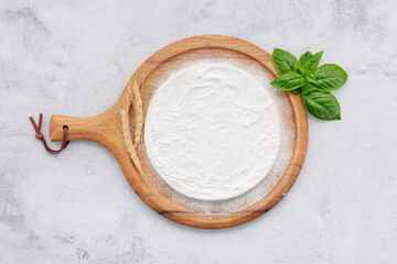 Pizza dough in wooden pizza platter set up on white concrete. Pizza tray on white concrete background flat lay and copy space.