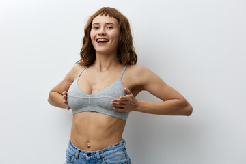 a happy, joyful woman stands on a bright background in stylish summer clothes and holds her hands on her chest, smiling broadly