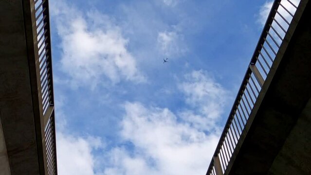 Distant airplane passing above diagonally between two bridge railings; in Ontario, Canada.