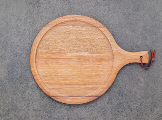 Empty wooden pizza platter set up on dark stone background . Pizza board on stone background flat lay and copy space.