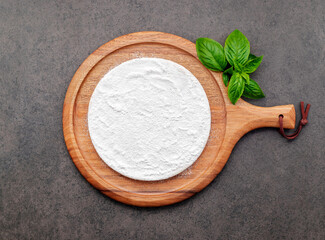 Pizza dough in wooden pizza platter set up on dark concrete. Pizza tray on dark concrete background flat lay and copy space.