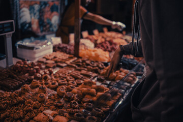 The hand points to the goods in the market counter with oriental sweets.