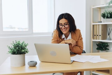 Business woman working in the office at her desk with a laptop, smile and business dialogue via video link, hand gestures in dialogue, online communication