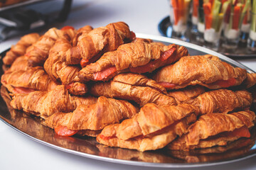 Catering table, beautifully decorated banquet table with variety of different food snacks, sandwiches, croissants and appetizers on party event or celebration, delicatessen setting, coffee break