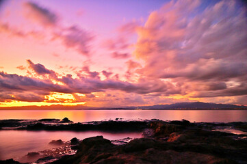 江の島の岩場から日没の湘南海岸を望む