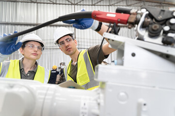 Engineer caucasian man and woman work together at machine robot factory