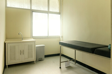 A small examination room with a bed and hand basin inside a hospital in Thailand.