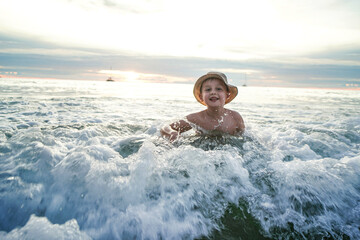 Happy boy having fun in the sea, swimming and playing in the waves.