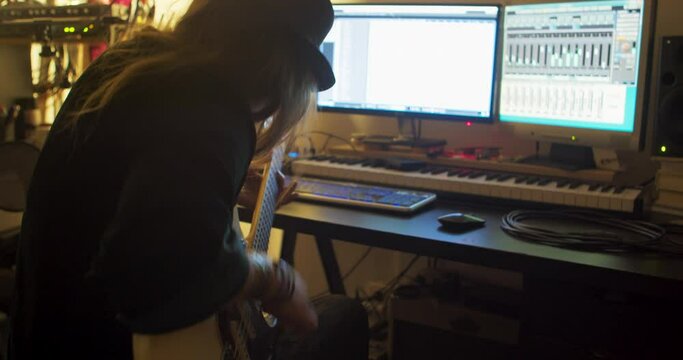 Woman playing electric guitar inside a recording studio. Medium handheld shot