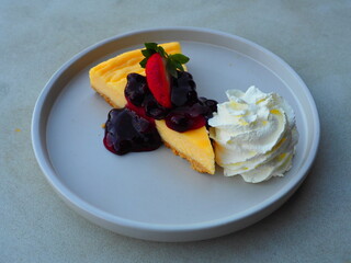Traditional classic cheesecake serving with whipping cream and fresh blueberry. Famous sweet dessert menu in coffee and bakery shop.