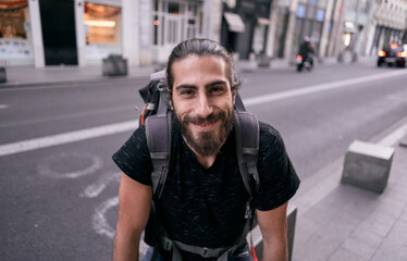 caucasian guy with a beard big backpack on his back smiling at camera happy on a city street, valencia, spain