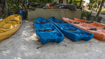 Colorful canoes stand in a row on the sand. Equipment for canoeing is laid nearby.Seychelles.