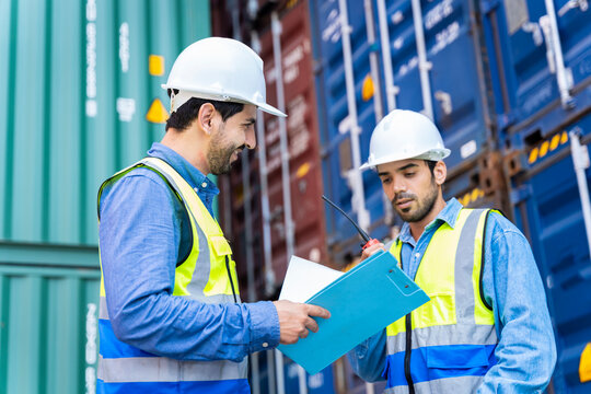 Two male engineers in a container shipping company Consulting to check the order for the container that is responsible	
