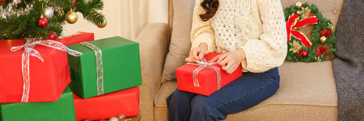 Christmas celebration concept, Young asian woman sitting on the couch and opening christmas gift