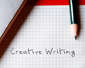 Pencil on note paper writing text CREATIVE WRITING, means imaginative, embellished, outside-the-box...
