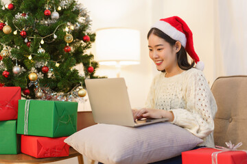 Christmas celebration concept, Young asian woman in santa hat working and shopping online on laptop