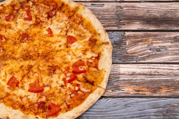 Hot pizza with melted cheese on a rustic wooden background. Homemade pizza ready to eat. Italian food.