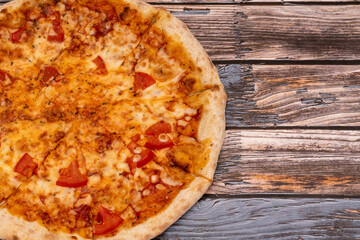 Hot pizza with melted cheese on a rustic wooden background. Homemade pizza ready to eat. Italian food.