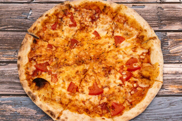 Hot pizza with melted cheese on a rustic wooden background. Homemade pizza ready to eat. Italian food.