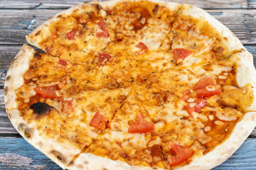 Hot pizza with melted cheese on a rustic wooden background. Homemade pizza ready to eat. Italian food.