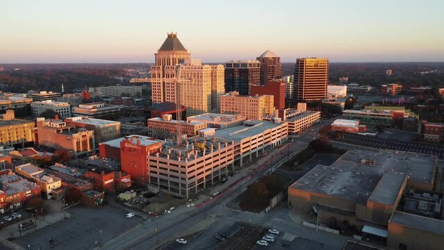 Reverse Aerial of down town Greensboro, NC with crane and construction in shot at Sunrise