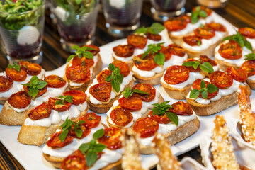 Fototapeta na wymiar Sandwiches with sun-dried tomatoes and soft cheese on the buffet table. Catering for holidays and events. Close-up.