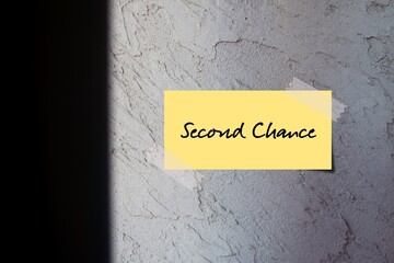Rough gray cement wall with yellow handwritten text note SECOND CHANCE, means new or more opportunity to try something again after failing one time
