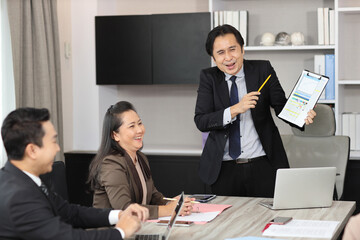 Collaborative process of young asian business people team working together discussing, researching, brainstorming and planning work at business meeting in modern office building and city background