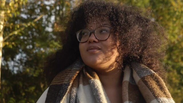 Smiling Black woman with curly hair portrait video in autumn forest. slow motion shot.