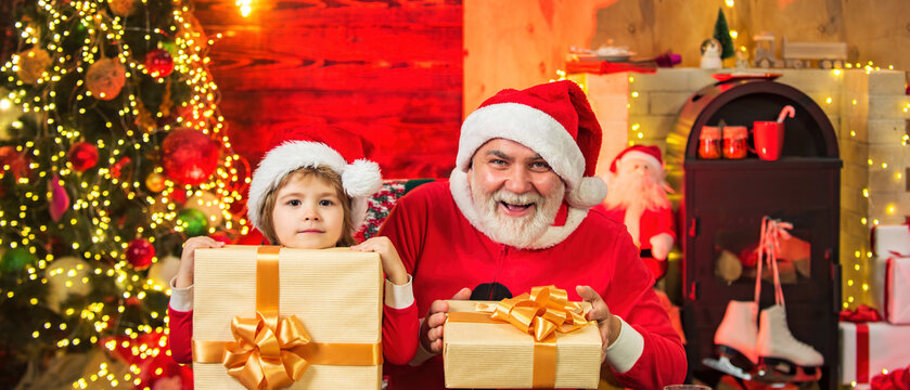 Funny little Santa grandfather and son holding bag with presents. Santa child grandfather and grandson. Child play with real Santa near christmas tree.