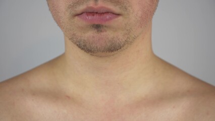 A young man touches the stubble on his chin with his hand. Face close-up.