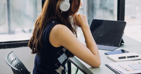 Young business woman sitting in office at table and using smartphone. On desk is laptop and tablet computer, on screen charts and graphs. Woman analyzing data. Student learning online.