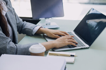 Young business woman sitting in office at table and using smartphone. On desk is laptop and tablet computer, on screen charts and graphs. Woman analyzing data. Student learning online.