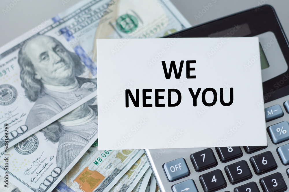 Poster we need you, message on the card on the background of a calculator with dollar bills on the table, a