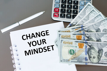 Change Your Mindset text notepad on the table next to the calculator, pen and dollar bills