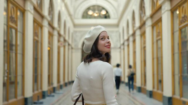 Young Parisian woman in a white beret walking in a gallery