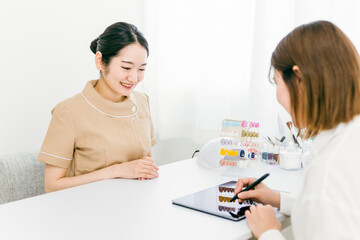 ネイルサロンでタブレットの契約書に電子サインするカウンセラースタッフと相談する日本人女性
