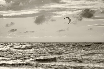 Surfing with kite on stormy waves in summer evening