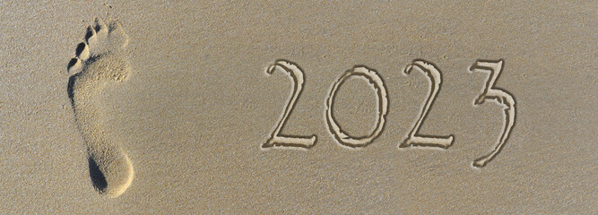 2023 written on the sand next to a footprint