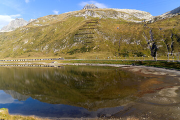 Beautiful landscape at Oberalppass with lake and reflections of mountain panorama on a sunny late...