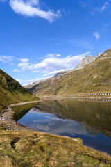Naklejka na ściany i meble Beautiful landscape at Oberalppass with lake and reflections of mountain panorama on a sunny late summer day. Photo taken September 5th, 2022, Oberalp Pass, Switzerland.