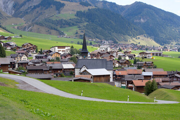 Fototapeta na wymiar Scenic view of mountain village Rueras, Canton Graubünden, with church on a blue cloudy late summer day. Photo taken September 5th, 2022, Rueras, Switzerland.