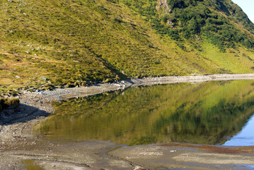 Railway station Oberalppass with lake and reflections of mountain panorama on a sunny late summer...