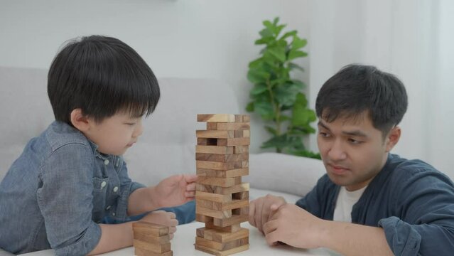 Happy single father playing  learning games and puzzles domino with the little boy. Funny family is happy and excited in the house. Father and son having fun spending time together. Good daddy