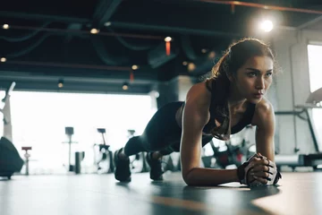 Crédence de cuisine en verre imprimé Fitness Young woman doing plank exercise while exercising in gym.