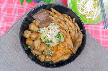 Chicken noodles with chicken feet, chicken thighs, chicken joints and side vegetables, bean sprouts, sliced bitter gourd.