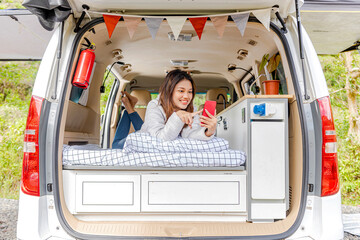 Asian woman using mobile phone inside the campervan