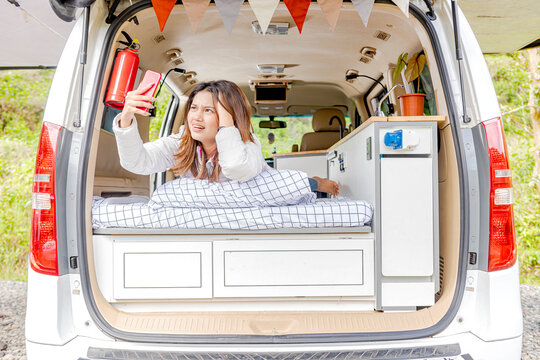 Asian Woman Searching The Signal For Her Mobile Phone Inside The Campervan