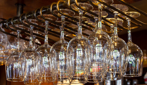 Shiny wine glasses hanging on a metallic structure in a bar, Paris, France.
