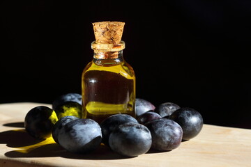 olive oil in a bottle and black olives on wooden table	
